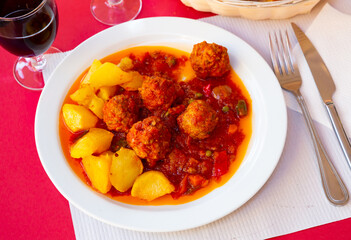 Albondigas, hot stew tomato soup with meatballs and vegetables in a white plate on the table