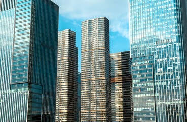 Fototapeta premium Modern skyscrapers reflect sunlight against a clear blue sky in an urban landscape in a bustling city