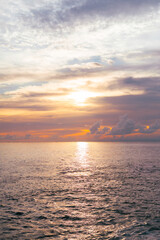 Stunning sunset over calm sea with glowing orange clouds and soft twilight reflections in the water.