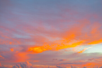Fototapeta premium Colorful twilight sky filled with dramatic orange clouds during a golden sunset.