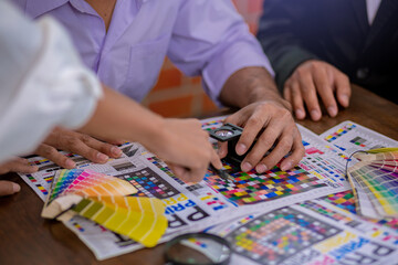 Team graphic designer checking print quality of media graphics proof print and color guides in...
