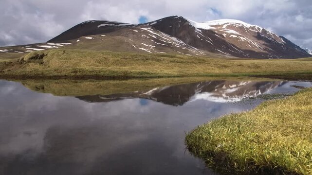 Footage depicts the Tien Shan Mountains, also known as the 'Celestial Mountains', with a valley reflecting the majestic mountains and clouds in the Arabel Plateau of Kyrgyzstan.