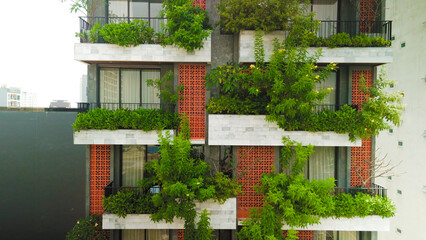 Green clad urban building featuring living walls and balcony gardens, representing contemporary...