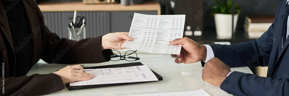 Poster header with colleagues examining financial documents in office