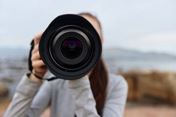 Young woman photographer focusing on the camera with a scenic outdoor background, showcasing...