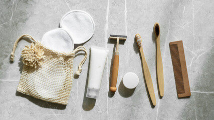 Hygiene products as bamboo toothbrushes, toothpaste, reusable pads, safety razor on grey marble,...