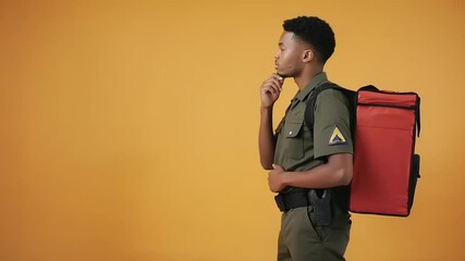 Delivery person in uniform, carrying insulated bag, against yellow backdrop