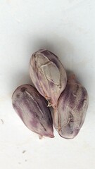 Three purple shallots arranged together on a neutral background, showcasing their unique shape and texture.
