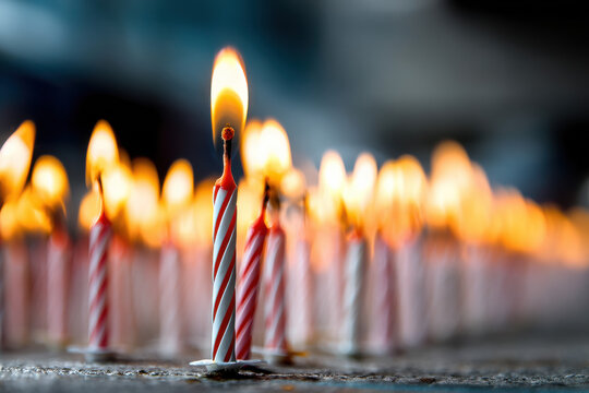 birthday candles placed in a repetative pattern with one candle lit