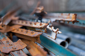 Pile of rusty weathered metal channels in the yard. construction material, shallow depth of field.