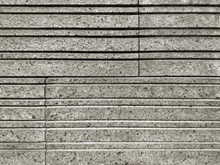 Striped cut flattened grey stone wall cladding stacked on one another. Andesite stone or paving...