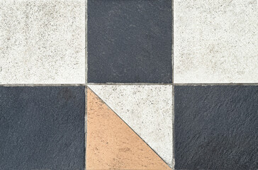 Close up of geometrical tiles in square and triangular pattern. In white, black, and orange color. Seamless background texture.