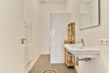 A sleek and contemporary bathroom featuring white tiles, a wall-mounted sink, and elegant wooden shelving for storage. Ideal for a serene aesthetic.