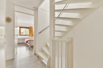 A modern spiral staircase leads from a bright, welcoming room adorned with wooden flooring and...