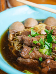 Braised beef noodle soup set on wooden table.