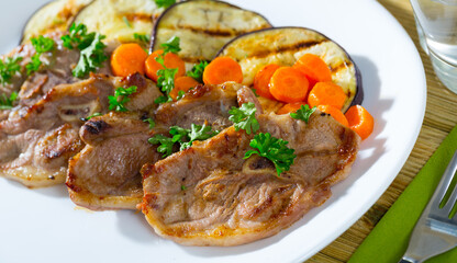 Tasty mutton loin chops grilled with eggplant slices and carrots garnished with fresh parsley