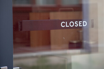 closed text sign hanging inside a restaurant store office or other door entrance
