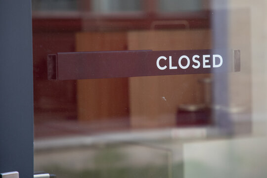 closed text sign hanging inside a restaurant store office or other door entrance