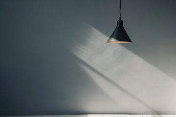 A closeup of the light from an industrial pendant lamp shining on a grey wall, creating soft shadows and highlights. 