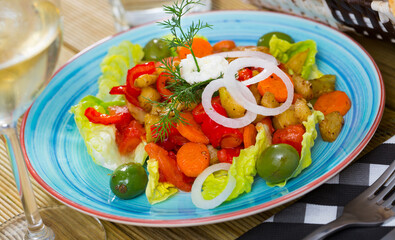 Plate of delicious salad with baked potato, pepper and carrot served with fresh onion