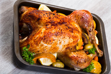 Tasty turkey baked with vegetables and apples, served with lemon slices and greens in baking dish