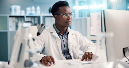 Computer, black man and scientist typing in lab for medical research, discovery or innovation,...