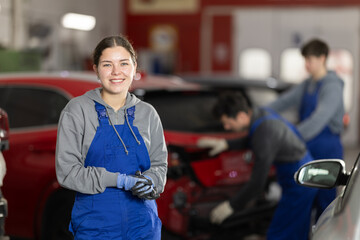 Girl employee performs repairs to external parts of car body and internal components of vehicle. Worker is busy restoring car after damage