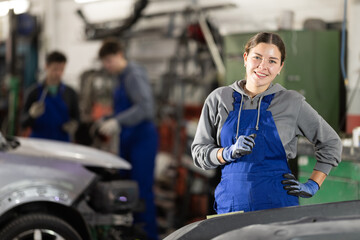 Girl employee performs repairs to external parts of car body and internal components of vehicle....