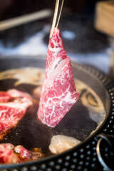 Take put sliced raw beef it in boiling pot Shabu shabu hotpot style in Japanese restaurant. Shabu...