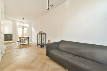 A spacious and bright modern interior featuring stylish furniture and warm wooden flooring. Natural light enhances the minimalist aesthetic of the space.