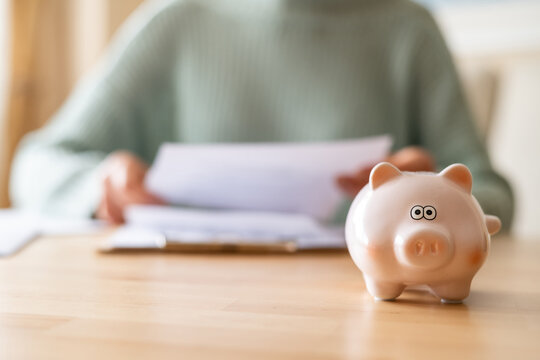 Woman reviewing domestic bills while managing monthly expenses, with a piggy bank symbolizing savings and effective financial planning for a secure future