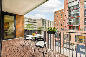 A contemporary balcony featuring a table and chairs, overlooking a vibrant cityscape with modern architecture and greenery.