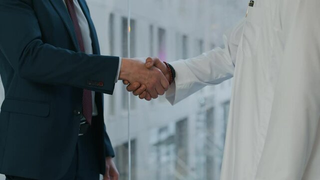 Cropped shot of multicultural male entrepreneurs shaking hands at modern office space