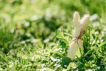 Handmade fabric Easter bunnies in yellow and green placed on vibrant green grass under bright spring sunlight