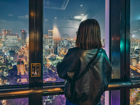 Tokyo, Japan - March 24, 2025: Visitor at Tokyo Tower main deck gazing out over illuminated city skyline at night