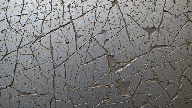 Scratched and scored metal surface, exhibiting a network of fine, interlacing abrasions alongside deeper gouges and impacts