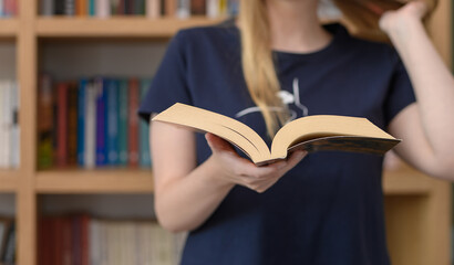 Młoda dziewczyna czytająca papierową książkę w publicznej bibliotece  © Paweł Kacperek