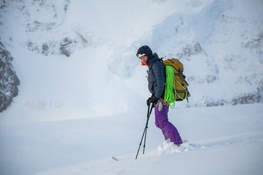 Woman backcountry skier stands squinting in a snow storm