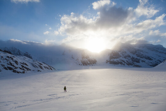 Backcountry skier skis down glacier surrounded by mountains