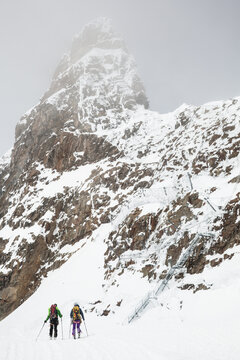 Backcountry skiers below cliff with rockfall nets at Jungfraujoch