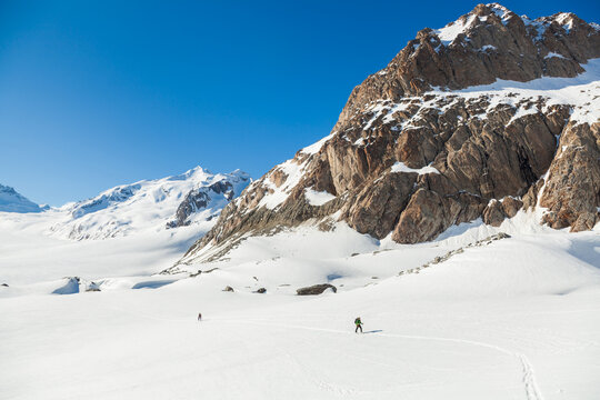 Backcountry skiers below mountain peaks on Aletsch Glacier
