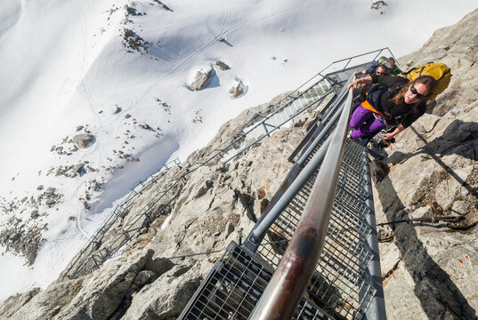 Backcountry skiers climb stairs in cliff to Konkordia Hut