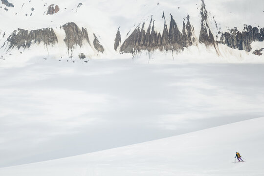 Backcountry skier skis down mountain with fog filling the valley below