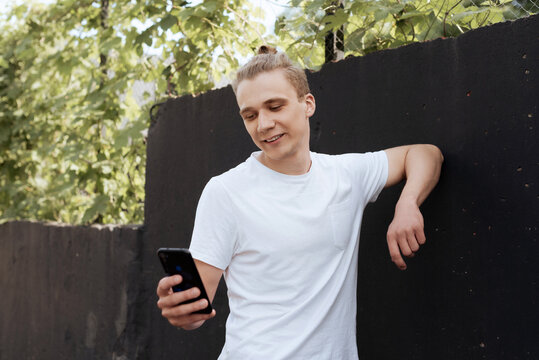 Smiling young man using smartphone outdoors