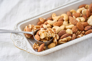 白い器に盛り付けたミックスナッツとスプーン