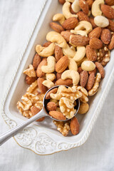 白い器に盛り付けたミックスナッツとスプーン
