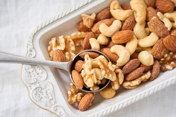 白い器に盛り付けたミックスナッツとスプーン