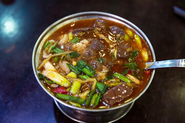 Taiwanese Wugeng Changwang, rich and spicy pork intestine stew, served in a hot pot, featuring duck blood, green onions, and garlic.
