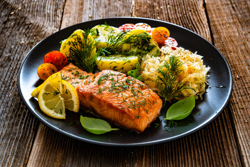 Seared salmon steak with boiled potatoes and sauerkraut on wooden table