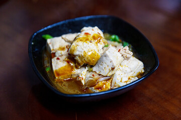 Braised stinky tofu cubes served with pickled cabbage in soy-based broth, classic Taiwanese night market dish in white ceramic bowl